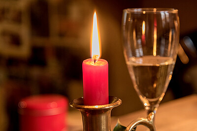 Rote Kerze neben einem Sektglas